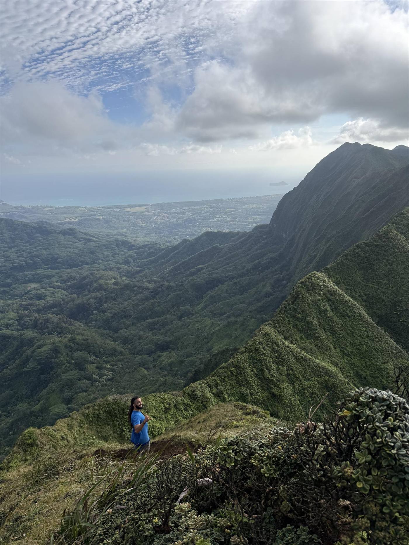A hiker throwing a shaka high above the Windward coast.